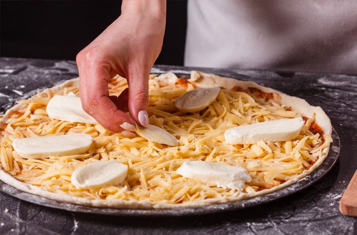 Proces tworzenia pizzy quattro formaggi - nakładanie sera