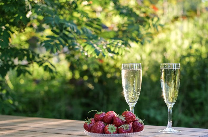 Dwa kieliszki prosecco w towarzystwie letnich truskawek