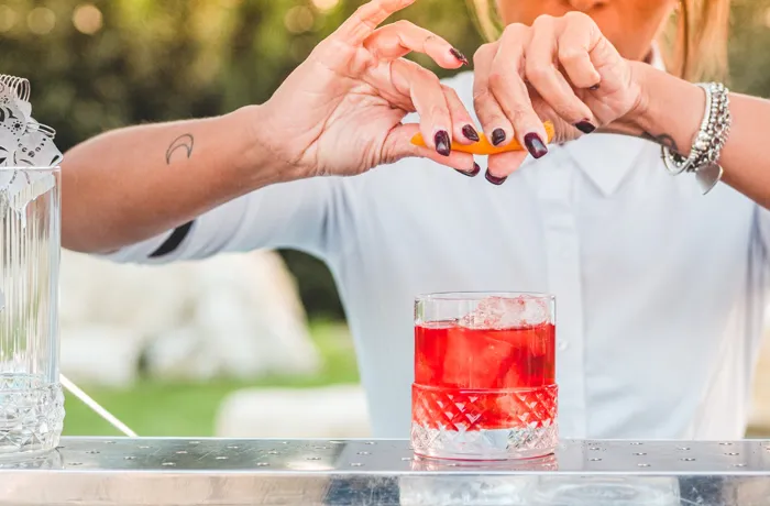 Barmanka przygotowuje koktajl Negroni z dodatkiem skórki pomarańczy